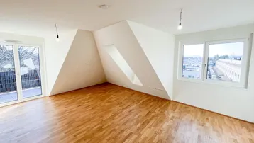Helles Zimmer mit Dachschrägen, Parkettboden und Zugang zu einem Balkon.