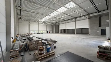 Große, leere Lagerhalle mit hoher Decke, Oberlichtern und Betonboden, derzeit im Bau.