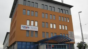Modernes Bürogebäude mit orangefarbener Fassade, blauer Glasfront und mehreren Etagen.