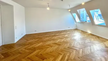 Helles Zimmer mit Fischgrätparkett, Dachschrägen und mehreren Dachfenstern, ideal als Wohn- oder Schlafbereich.