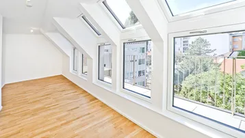 Helles Wohnzimmer im Dachgeschoss mit Parkettboden, Dachfenstern und französischem Balkon.