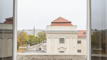 Blick von einem Balkon auf historische Gebäude und die Stadtlandschaft unter einem bewölkten Himmel.