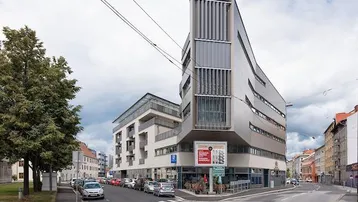 Modernes Gebäude an einer Straßenecke mit Geschäften im Erdgeschoss und Wohnungen darüber.