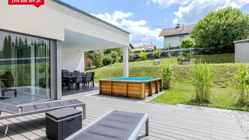 Große Holzterrasse mit Liegestühlen, Essbereich und einem kleinen Pool im Garten.