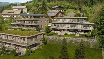 Luftaufnahme eines modernen Wohnkomplexes mit mehreren Gebäuden, umgeben von viel Grün und Bäumen.