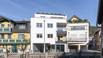 Modernes Mehrfamilienhaus mit Balkonen und Solaranlage in städtischer Umgebung.