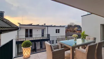 Geräumige Terrasse mit modernen Gartenmöbeln und weitem Blick über die Umgebung bei Sonnenuntergang.