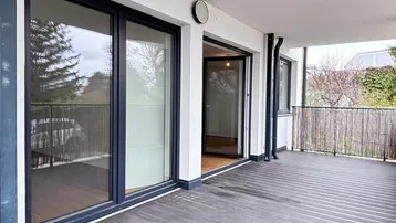 Geräumiger Balkon mit dunklem Holzboden und Schiebetüren, ideal für entspannte Stunden im Freien.