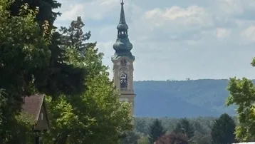 Malerischer Blick auf eine Kirche und die umliegende Landschaft mit Bergen im Hintergrund.