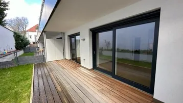 Geräumige Holzterrasse mit direktem Zugang zum Garten und großen Schiebetüren.