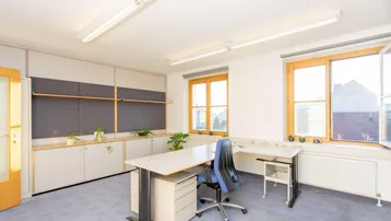 Geräumiges Büro mit Teppichboden, großen Fenstern und integrierten Schränken für eine funktionale Arbeitsumgebung.