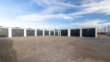 Reihe moderner Lagerboxen mit grauen Türen unter einem weiten blauen Himmel.