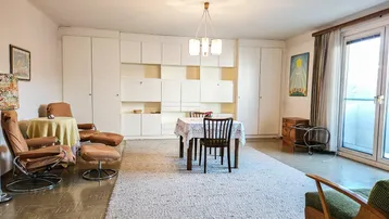 Geräumiger Wohn- und Essbereich mit Vintage-Möbeln, Einbauschränken und Zugang zum Balkon.