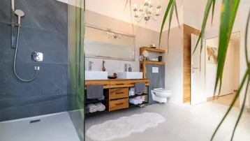 Elegantes Badezimmer mit großer begehbarer Dusche, Doppelwaschbecken und modernem Design.