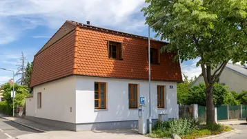 Charmantes Einfamilienhaus mit Mansarddach und traditionellen Ziegeln an einer Straßenecke.