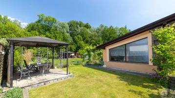 Gepflegter Gartenbereich mit Rasenfläche, Gartenlaube und Blick ins Grüne.