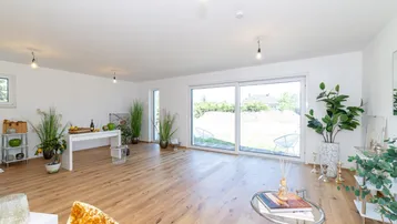Heller, offener Wohn- und Essbereich mit Holzboden und großem Zugang zum Garten.