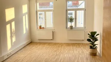 Heller und geräumiger Büroraum mit Parkettboden, großen Fenstern und viel natürlichem Licht.