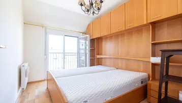 Schlafzimmer mit Holzboden, Einbauschränken und Zugang zu einem französischen Balkon.
