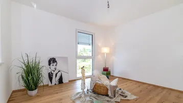 Helles Zimmer mit Holzboden, großem Fenster und moderner Dekoration mit Pflanzen und Kunst.