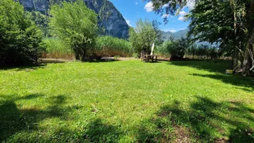 Großer Gartenbereich mit Rasenfläche, Sitzgelegenheiten und direktem Zugang zum See mit Bergblick.