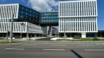 Modernes Bürogebäude mit markanter Architektur und Verbindungsbrücke unter blauem Himmel.
