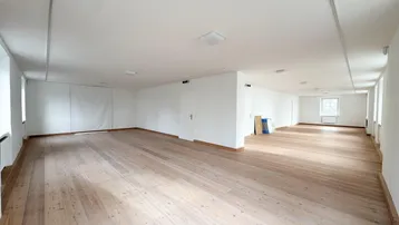 Großer, heller Büroraum mit hellem Holzboden und weißen Wänden, ideal für flexible Nutzung.