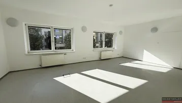Heller Büroraum mit großen Fenstern, die viel Tageslicht hereinlassen und einem funktionalen Bodenbelag.