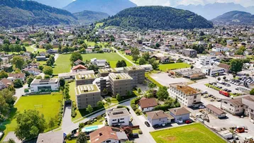 Luftaufnahme der Wohnanlage eingebettet in die grüne Umgebung mit beeindruckendem Bergblick.