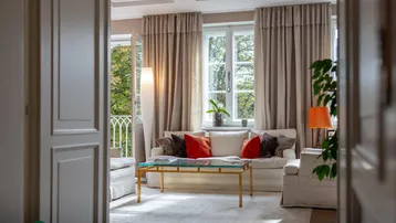 Helles Wohnzimmer mit bequemen Sofas, einem Couchtisch und Blick ins Grüne durch große Fenster.