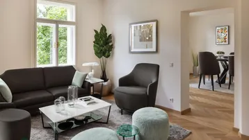 Helles Wohnzimmer mit modernem Mobiliar und Blick in den Essbereich, ausgestattet mit Fischgrätparkett.