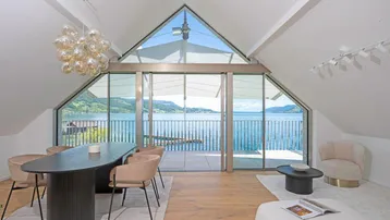 Heller Wohn- und Essbereich mit atemberaubendem Seeblick durch große Glasfronten.