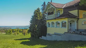 Gelbes Haus mit traditioneller Architektur und weitem Blick auf die Landschaft und einen See.