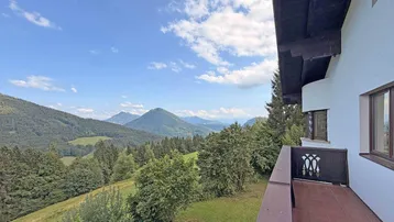 Geräumiger Balkon mit traditionellem Geländer und atemberaubendem Bergblick über die grüne Landschaft.