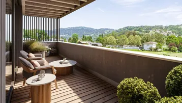 Geräumiger Balkon mit Holzboden, Sitzgelegenheiten und weitem Blick auf die grüne Landschaft.