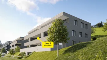 Moderne Wohnanlage mit mehreren Gebäuden an einem Hang, umgeben von grüner Landschaft und Bäumen.