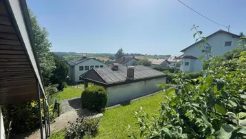 Blick über den grünen Garten mit Rasenfläche und umliegenden Häusern in ländlicher Umgebung.