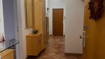Heller Flur mit Terrakotta-Fliesenboden und praktischen Holzschränken für Stauraum.