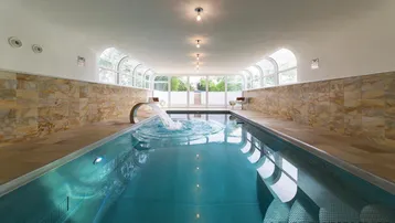 Innenpool mit Wasserspeier und breiter Treppe, umgeben von hellen Steinwänden.
