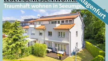 Mehrfamilienhaus mit gepflegtem Garten, einer Holzterrasse und Balkonen in grüner Umgebung.