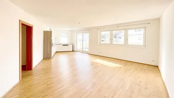 Heller, offener Wohn- und Essbereich mit Parkettboden und Zugang zur Terrasse.