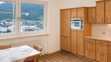 Gemütliche Küche mit Holzeinbauten, Essbereich und Fensterblick auf die umliegende Berglandschaft.