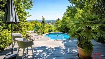 Geräumige Holzterrasse mit kleinem Pool, Liegestühlen und weitem Blick über die Landschaft.