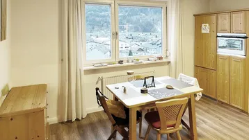 Gemütlicher Essbereich mit Holztisch, Stühlen und Blick auf die umliegende Berglandschaft.