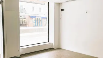 Heller, leerer Gewerberaum mit großen Schaufenstern und Blick auf die Straße, ideal für Einzelhandel.