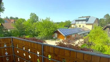 Blick vom Balkon auf die Nachbarschaft mit viel Grün und Solaranlagen.