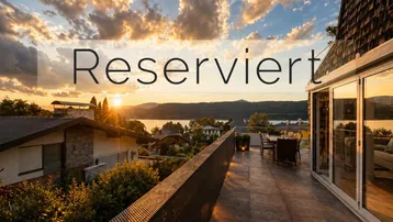 Großzügige Terrasse mit modernem Mobiliar, die einen atemberaubenden Blick auf den See und die Berge bei Sonnenuntergang bietet.