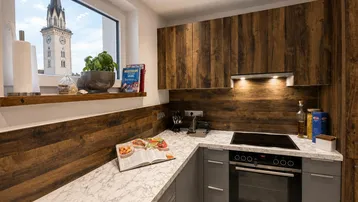 Moderne Küche mit Holzfronten, heller Arbeitsplatte und Blick auf einen Kirchturm.