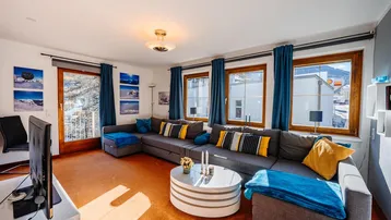 Helles Wohnzimmer mit großem Ecksofa, Teppichboden und Zugang zum Balkon mit Bergblick.