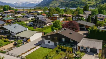 Luftaufnahme eines Hauses in einer Wohnsiedlung mit See- und Bergblick.